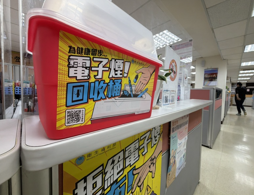 公共服務櫃檯上的紅色電子煙回收桶，貼有「電子煙回收桶」宣傳海報與回收插畫